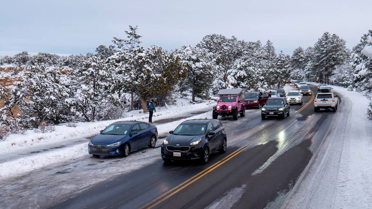 cars driving over icy patches in a roadway by a pull-off at a scenic overlook