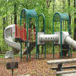 picture of  the Sweetgum Picnic area with picnic table, grill, and playground equipment.