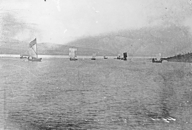 Black and white photo of boats with sails on a large body of water