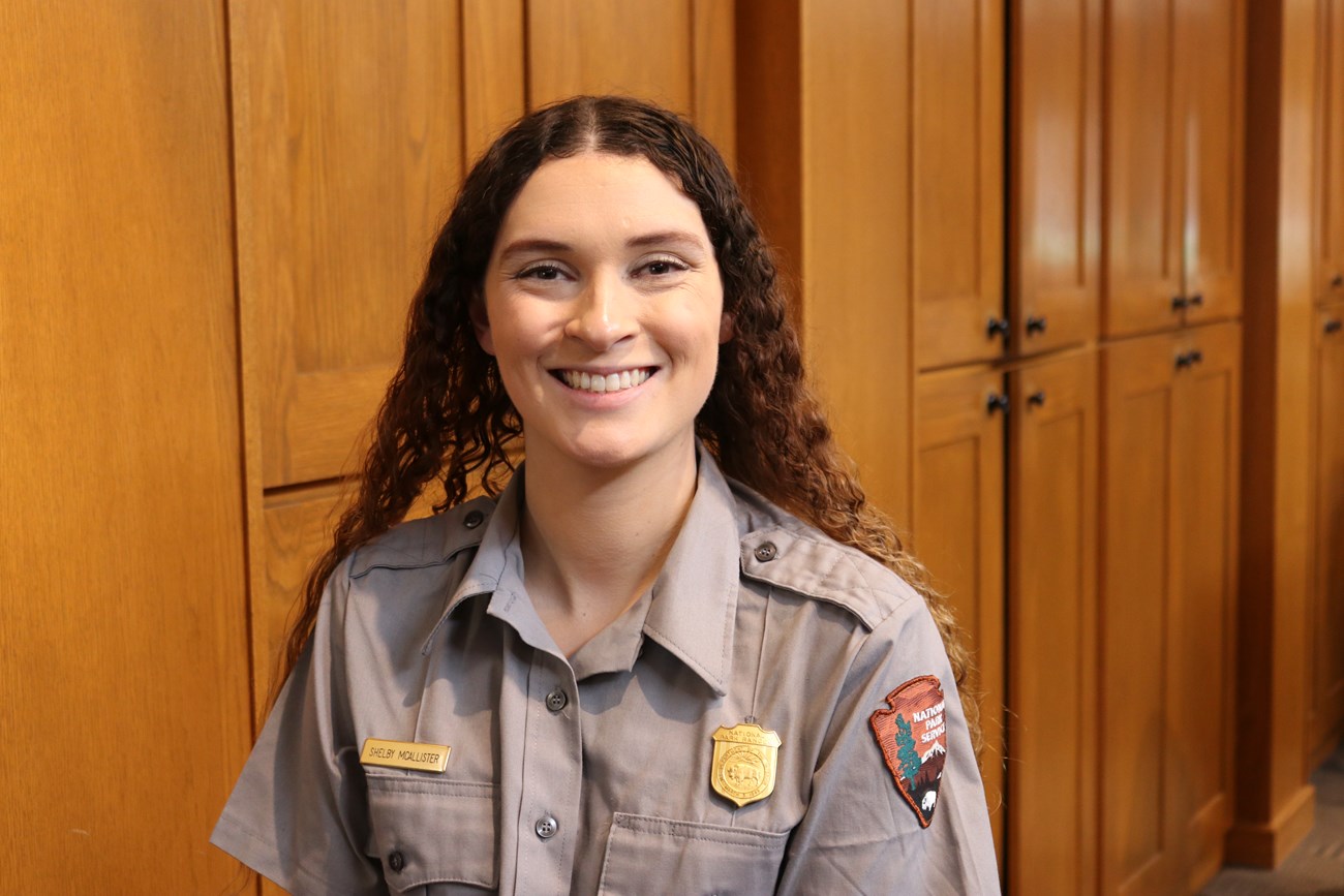 A smiling female ranger stands in front of cabinets