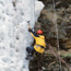 A winter visitor scales a column of ice with ropes and ice pick. A winter visitor scales a column of ice with ropes and ice pick.