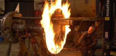 Workers at Steamtown use heat to expand a steel tire and place it on a locomotive wheel. NPS Photo, Bill Clark