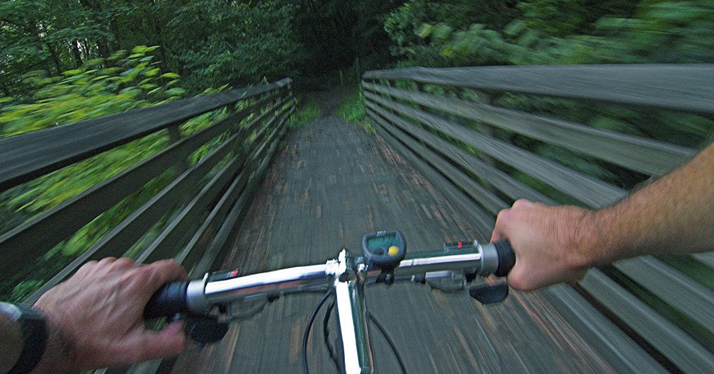 Biker grips the handlebars while mountain biking on a trail