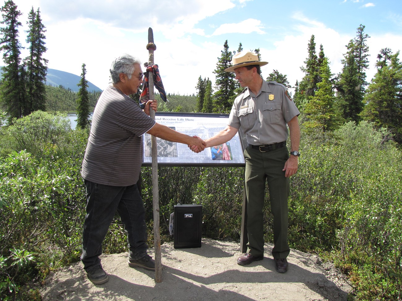 a park ranger shakes hands with a local man during a campground dedication