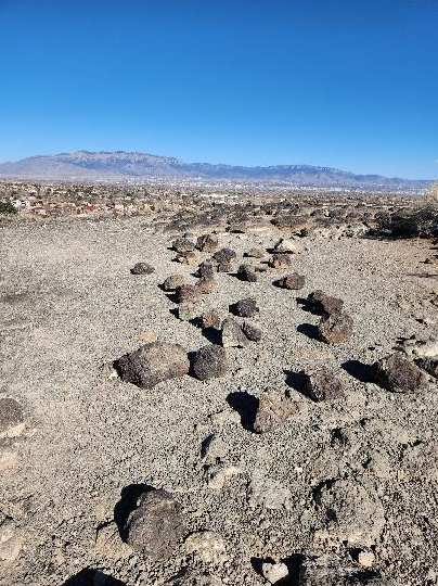 Many brick-sized black rocks scattered on a mesa top under a blue sky.