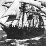 A historic photo showing a full-rigged ship with sails set.