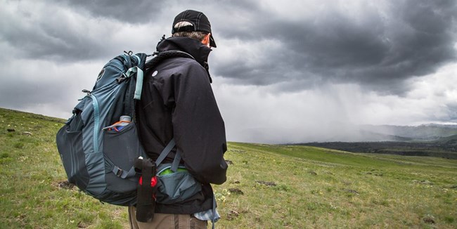 Hiker watches dark storm clouds