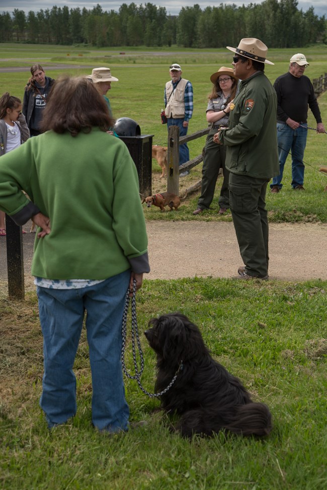 Woman and her dog listen to a park ranger.