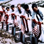 Sailors mourn those lost by laying wreaths over grave markers.