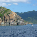 The view is shown from a boat, as it travels past a headland on the island of St. John. Looking across the water at the cut-away portion of the headland, you can see a geologic sill. The view is shown from a boat, as it travels past a headland on the island of St. John. Looking across the water at the cut-away portion of the headland, you can see a geologic sill.