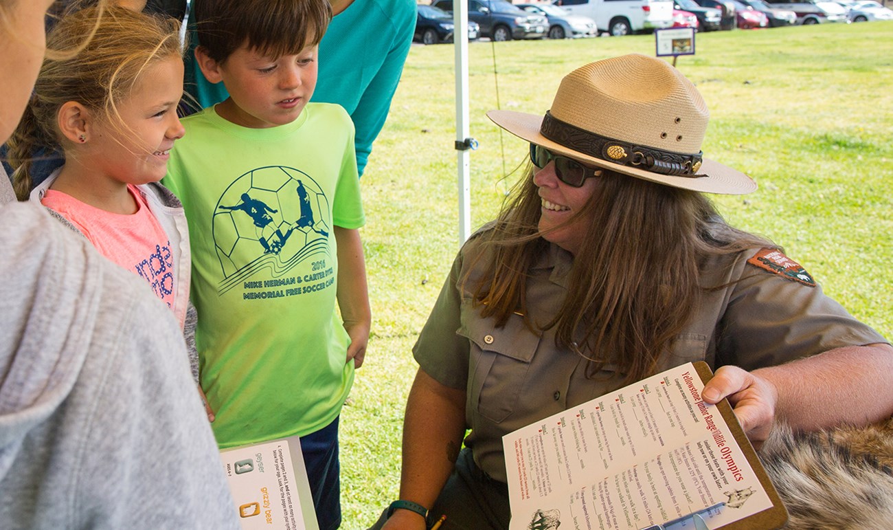 A park ranger shows an activity booklet to two young children.
