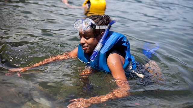 Kid swimming wearing a life jacket and goggles