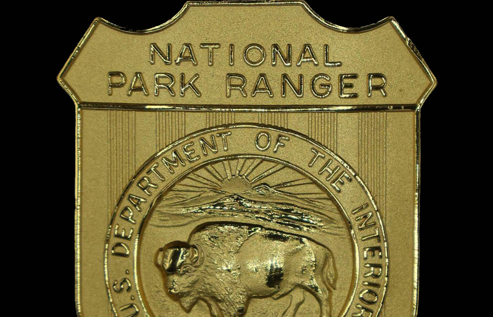 Gold shield-shaped badge marked National Park Ranger. Round seal in the middle has a bison with US Department of the Interior March 3, 1849 around it.