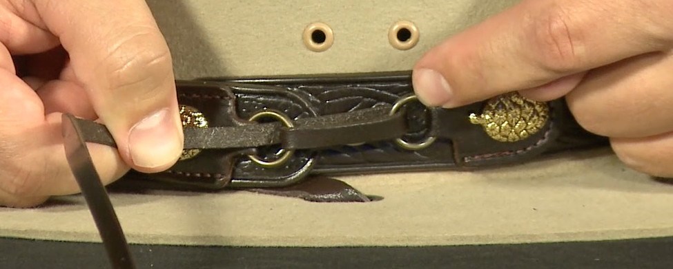 Tying the Hatband Step 3 A close-up of hands pulling the cord tight on the hatband of a ranger hat