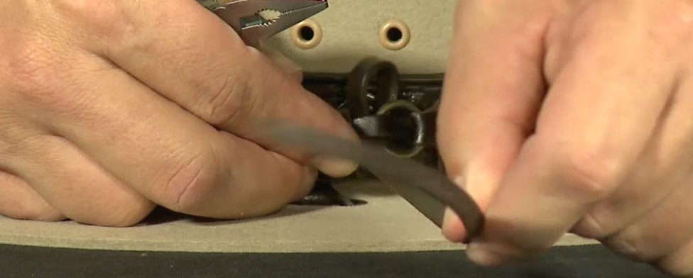 Tying the Hatband Step 6 A close-up of hands threading a cord through the center of a loop on the hatband of a ranger hat