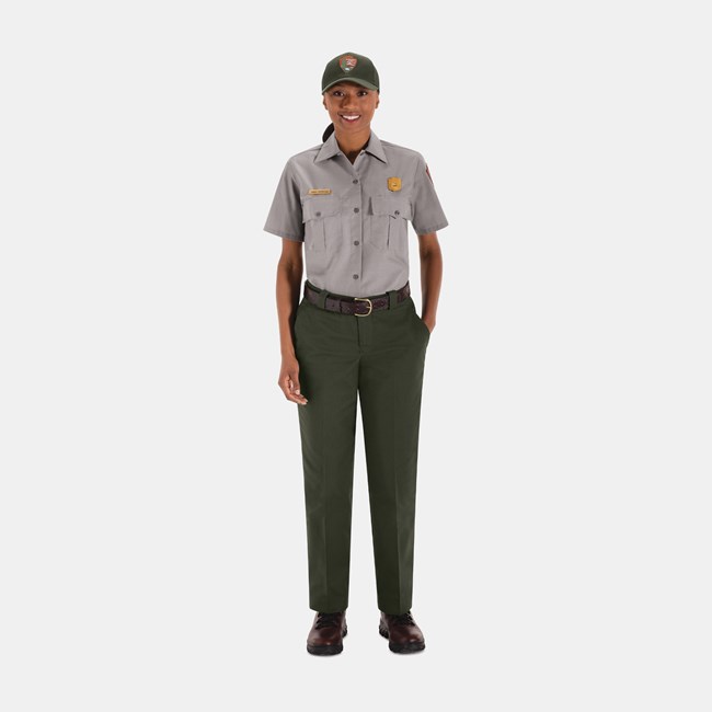 Summer Field Uniform An NPS employee wearing a green ball cap, gray short-sleeved shirt, green pants, and brown shoes