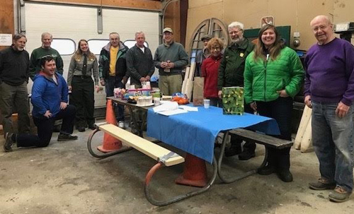 Group photo of sign shop volunteers in a workshop space