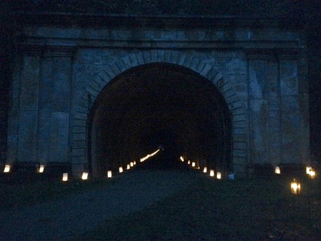 A railroad tunnel at night with luminaries.