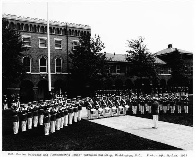 A large band performs in front of brick buildings