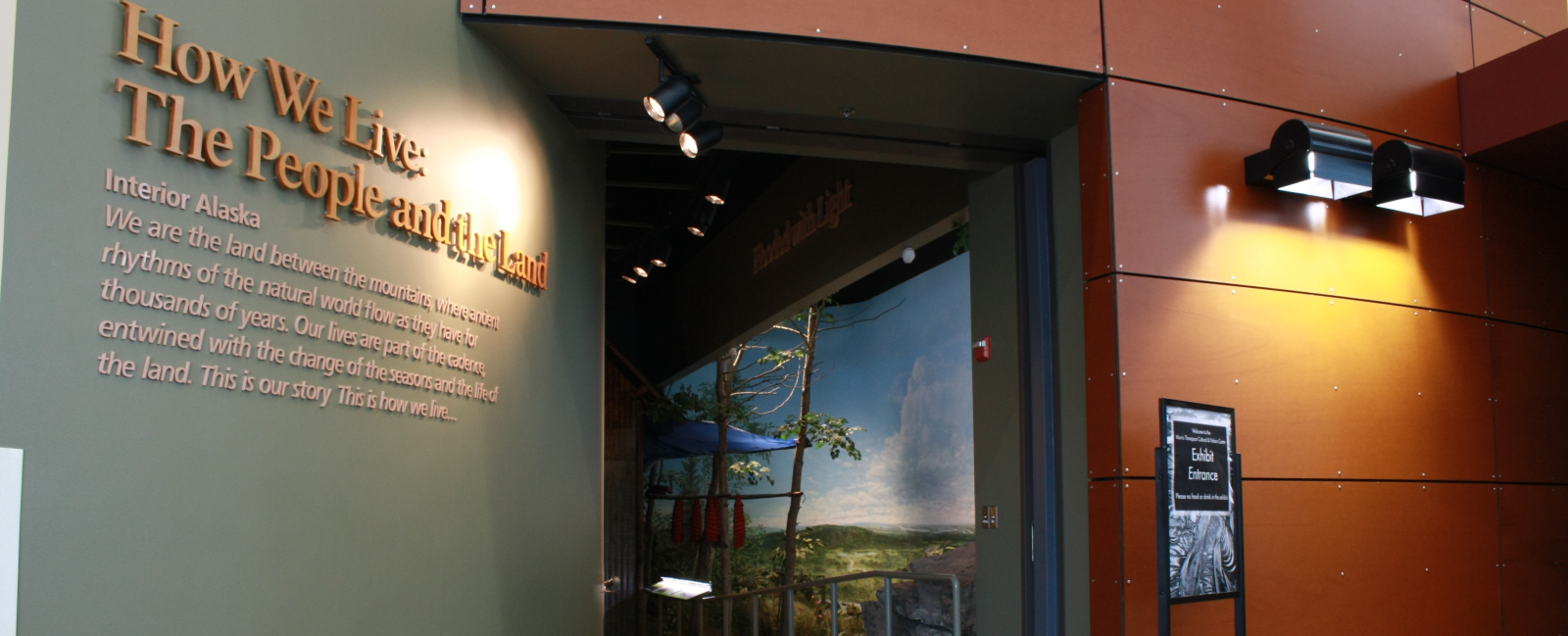 The exhibit entrance is surrounded by green wall with text on the left and a wooden wall on the right.