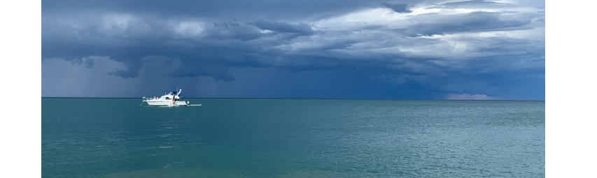 A white boat surrounded by water with dark clouds above.