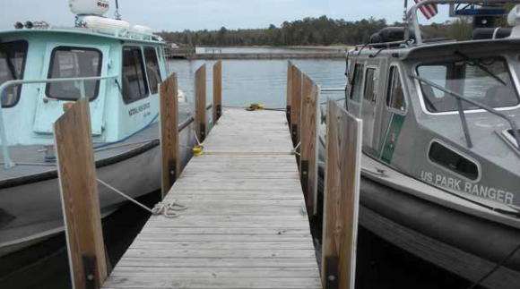 A wooden dock with two boats tied on either side.