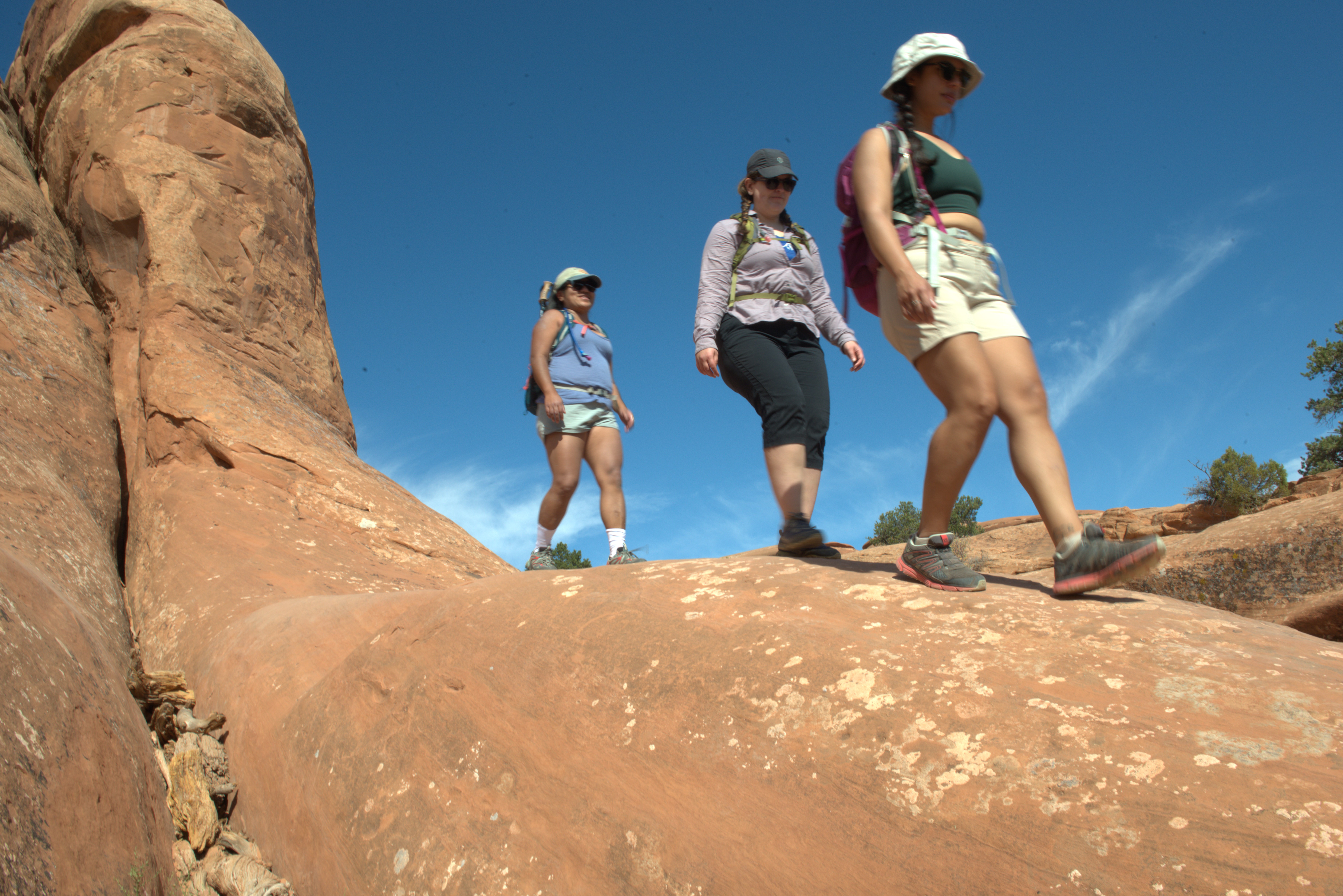 three women hiking on tan sandstone