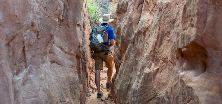 hiker in narrow gap between tall sandstone walls