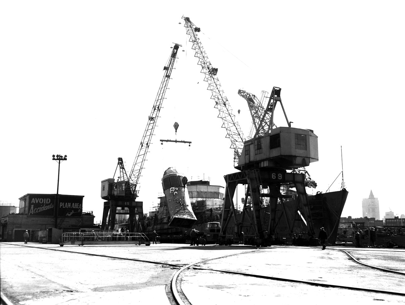 two portal cranes working together to lift a funnel off a ship onto a truck