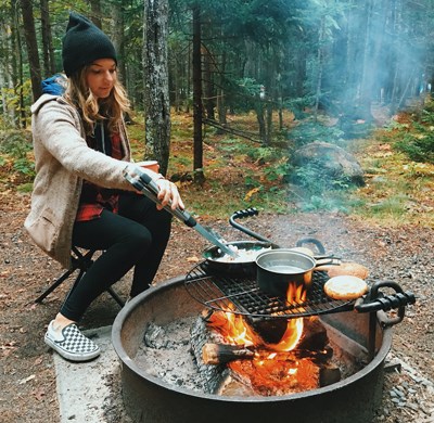 Photo courtesy of visitor Megan Carvalho of Little Compton, RI Woman makes breakfast over campground fire ring