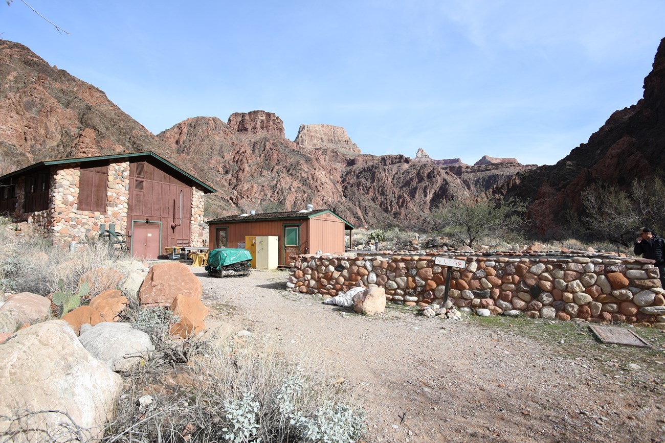 A person looks over rock formation walls near a building outside.