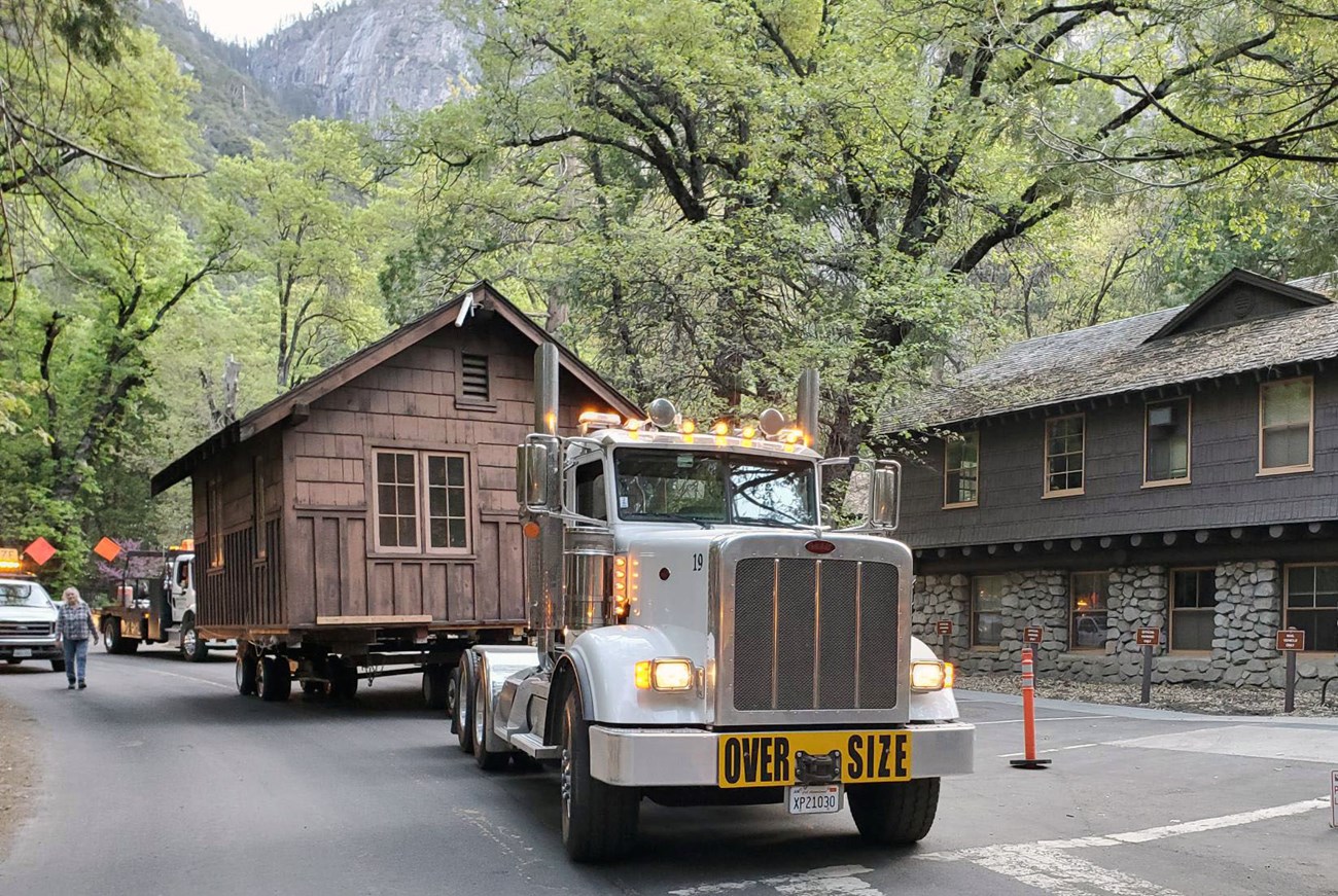 Tractor trailer drives wooden cabin through Yosemite Valley