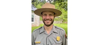 Evan Childress Evan smiling in his NPS uniform and flat hat.