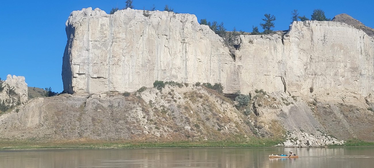 large bare rock cliff overlooking a river