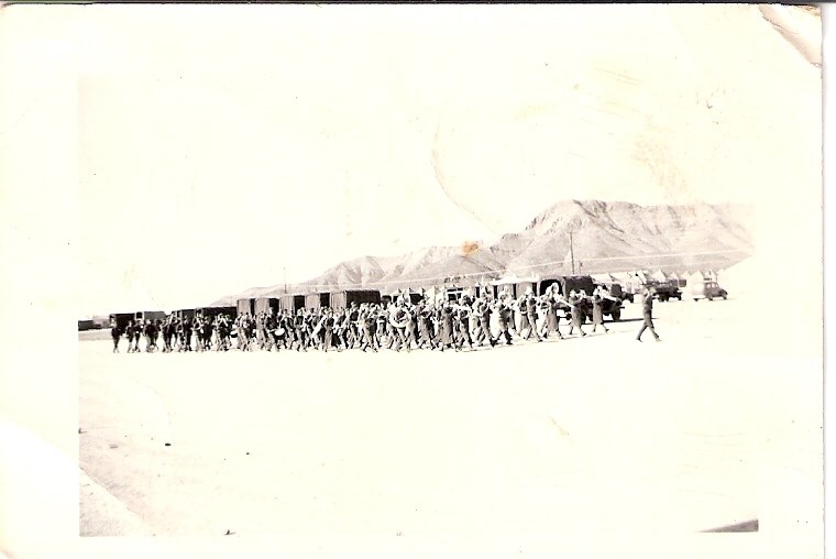 206th on parade at Fort Bliss,1941 large group of men with musical instruments on parade in desert landscape with mountains and tents in background