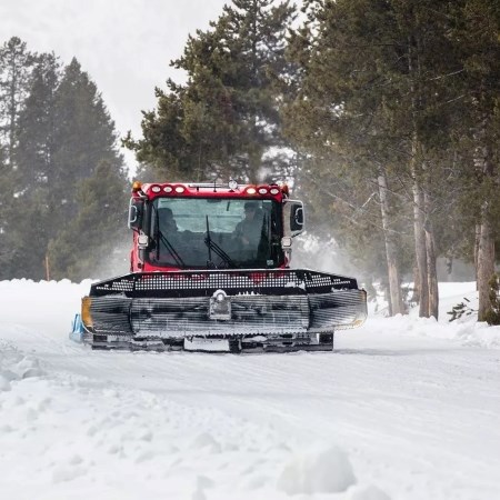 Grooming Roads in Winter a large groomer machine driving down a snow-covered road