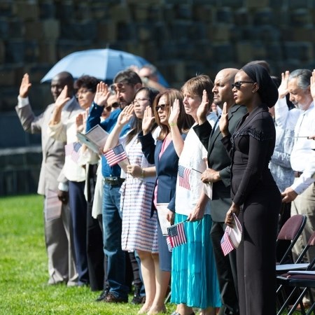 Hosting Naturalization Ceremonies a group of people holding their hand in the air as they take an oath