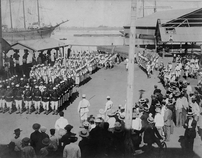 Military people in formation Military battalions stand in formation in front of a crowd of civilians
