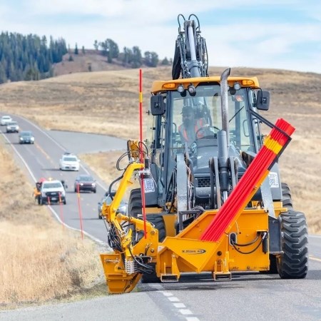 Preparing Park Roads for Winter Travel a person operating a large machine on a road