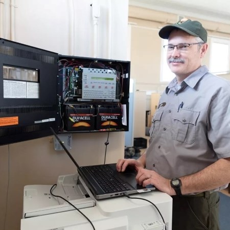 Installing Intelligent Alarms Systems a park ranger with a computer standing next to an alarm system
