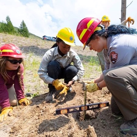 Replacing Trailhead Signs a group of young adults installing a post into the ground