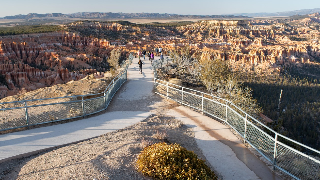 Visitors enjoy the Bryce Point Overlook Group of people at the end of a fenced overlook with a spectacular view of Bryce Canyon.