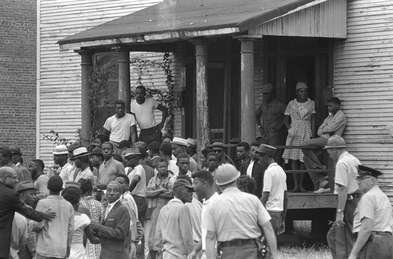 Crowd of African Americans in front of a house, looking toward the scene of the 16th Street Baptist Church bombing.