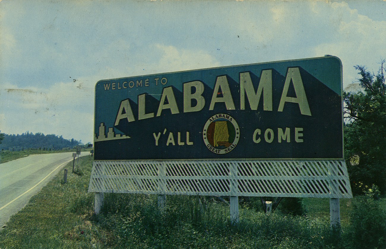 A highway sign that says "Alabama Y'all Come"