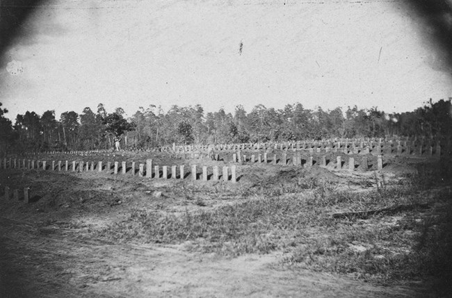 Photograph of the national cemetery as it appeared during the prison's operation, with rows of headstones on rough, uneven terrain. he cemetery looking across section K, or from in between sections J and K looking across J.