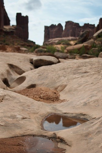 potholes with water carved into sandstone with rocky towers in the background