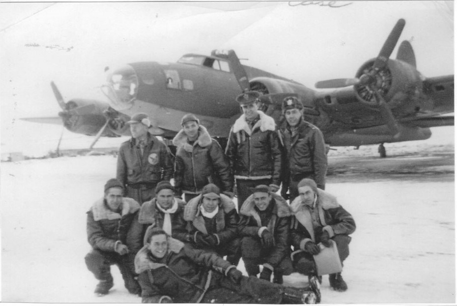 Black and white photo of two rows of white men in aviation gear in front of a propeller plane