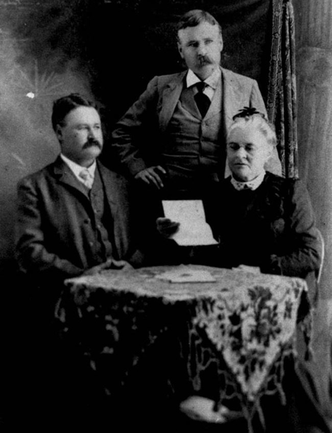 Anna Martin and two sons overlooking a document while seated at a table