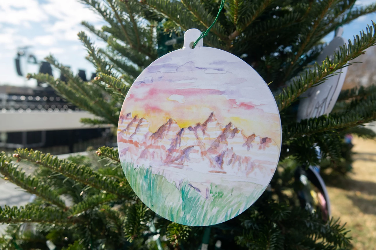 Badlands National Christmas Tree 2021 ornament with a drawing of the rugged terrain of badlands national park. The ornament is hanging from a christmas tree