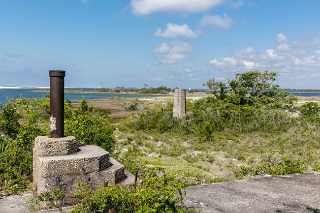 A historic concrete structure overlooks a remote grassy marshland.